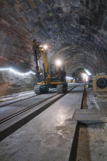 An excavator in an illuminated tunnel on rails, with a depth of perspective in the scene, construction of the Hermann Hesse railway, Calw, Black Forest, Germany