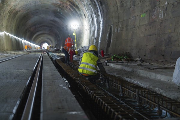 Construction workers in the tunnel working on the tracks. The scene is illuminated by strong light, construction of the Hermann Hesse railway, Calw, Black Forest, Germany