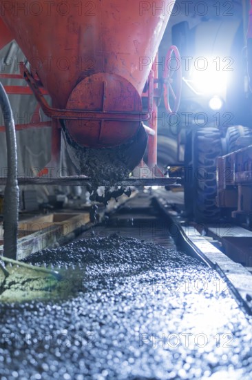 Concrete is poured from a construction vehicle in the tunnel. The area is brightly lit, construction of the Hermann Hesse railway, Calw, Black Forest, Germany