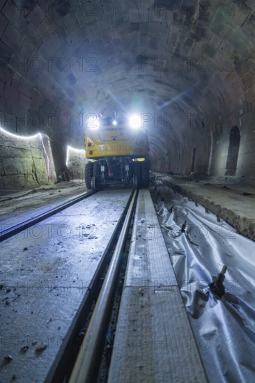 A yellow vehicle with bright lights stands in the tunnel, the rails are visible, construction of the Hermann Hesse railway, Calw, Black Forest, Germany