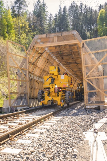 Yellow machine drives through a tunnel surrounded by wood, construction of the Hermann Hesse railway, Calw, Black Forest, Germany