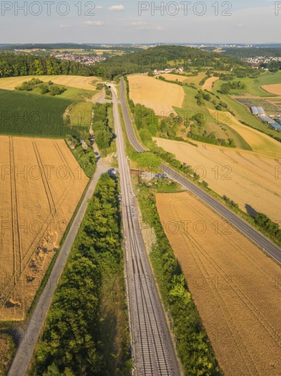 Bird's eye view of a summer landscape with fields, railway tracks and a road, surrounded by green vegetation, construction of the Hermann Hesse Railway, Calw, Black Forest, Germany