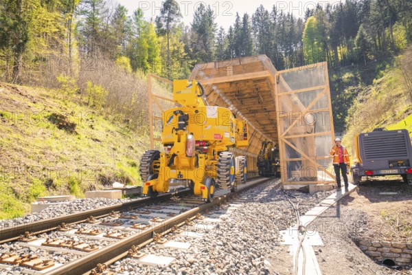 Yellow machine at the tunnel entrance with a worker next to it, construction of the Hermann Hesse railway, Calw, Black Forest, Germany