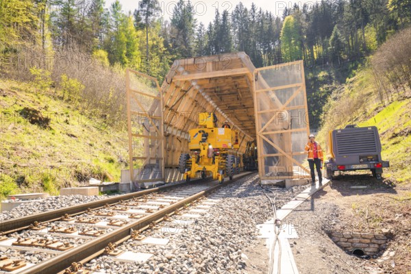 Machine and worker at the entrance to a tunnel in the forest, construction of the Hermann Hesse railway, Calw, Black Forest, Germany