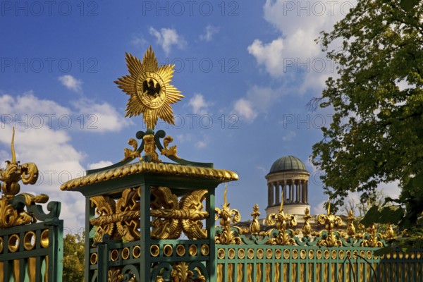 Golden star with black eagle on the fence of Charlottenburg Palace and dome of the Stüler Building, Berlin, Germany