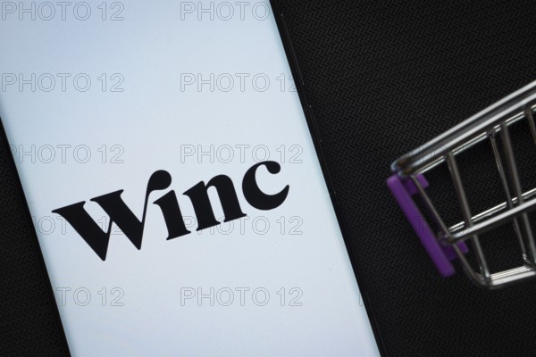Dhaka, Bangladesh- 03 July 2025: A smartphone displaying the Winc logo next to a miniature shopping cart on a background