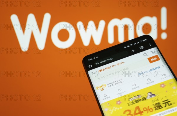 Dhaka, Bangladesh- 03 July 2025: Smartphone displaying wowma web interface against wowma logo background