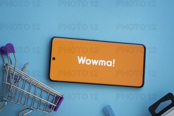 Dhaka, Bangladesh- 03 July 2025: Smartphone displaying wowma logo with shopping cart on a blue background