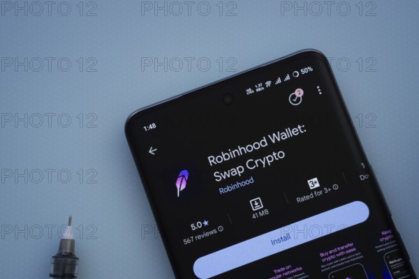 Dhaka, Bangladesh- 29 May 2025: On a blue surface, a smartphone displays the Robinhood Wallet app within the Google Play Store