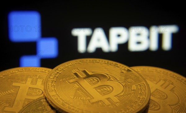 Dhaka, Bangladesh- 20 Sep 2025: Close-up of Bitcoin coins with thex Tapbit logo visible on a screen in the background
