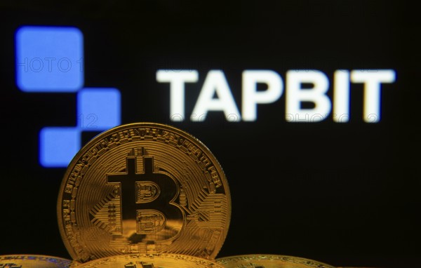 Dhaka, Bangladesh- 20 Sep 2025: Close-up of Bitcoin coins with thex Tapbit logo visible on a screen in the background