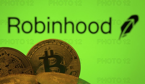 Dhaka, Bangladesh- 20 Sep 2025: Close-up of Bitcoin coins with the Robinhood Markets logo visible on a screen in the background