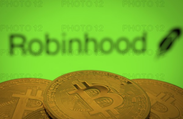 Dhaka, Bangladesh- 20 Sep 2025: Close-up of Bitcoin coins with the Robinhood Markets logo visible on a screen in the background