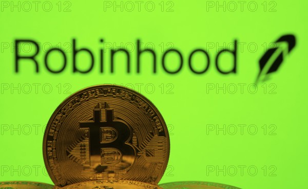 Dhaka, Bangladesh- 20 Sep 2025: Close-up of Bitcoin coins with the Robinhood logo visible on a screen in the background
