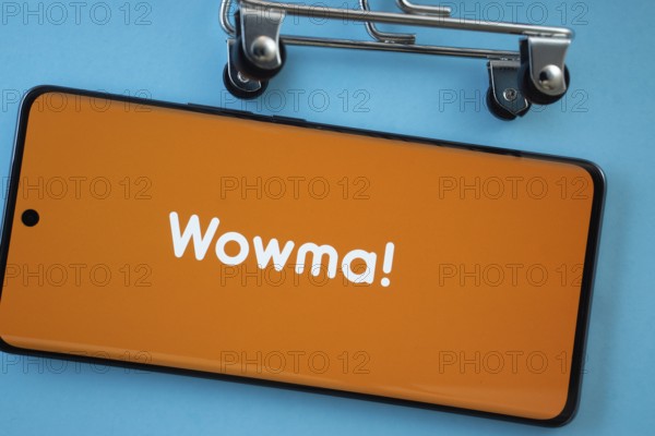 Dhaka, Bangladesh- 03 July 2025: Smartphone screen showing the wowma logo with shopping cart wheels on a blue background