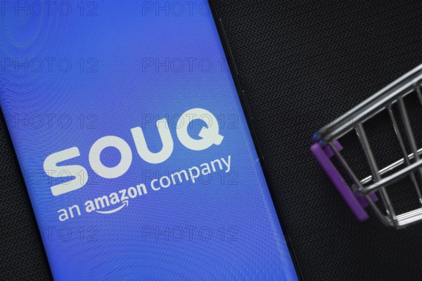 Dhaka, Bangladesh- 03 July 2025: A smartphone displaying the Souq logo next to a miniature shopping cart on a background