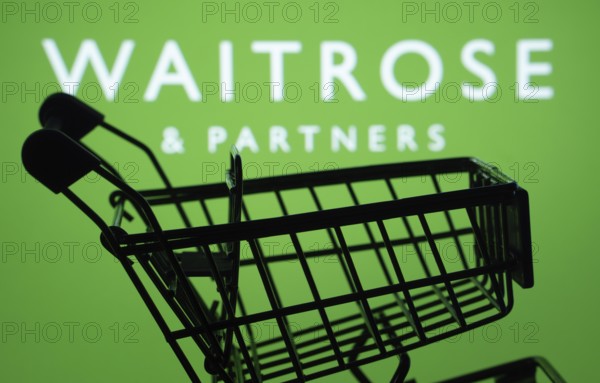 Dhaka, Bangladesh- 03 July 2025: Silhouette of a shopping cart in front of the Waitrose & Partners logo, symbolizing ecommerce and online shopping