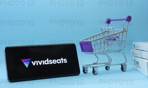 Dhaka, Bangladesh- 03 July 2025: Smartphone with VividSeats logo next to a small shopping cart and boxes against a blue background