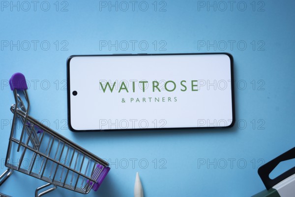 Dhaka, Bangladesh- 03 July 2025: Smartphone displaying Waitrose & Partners logo with shopping cart on a blue background