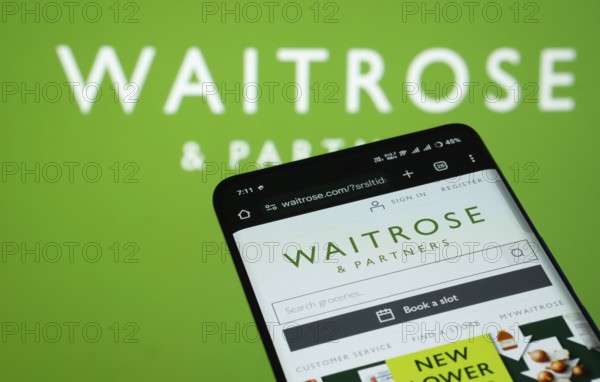 Dhaka, Bangladesh- 03 July 2025: Smartphone displaying Waitrose & Partners web interface against (....) logo background