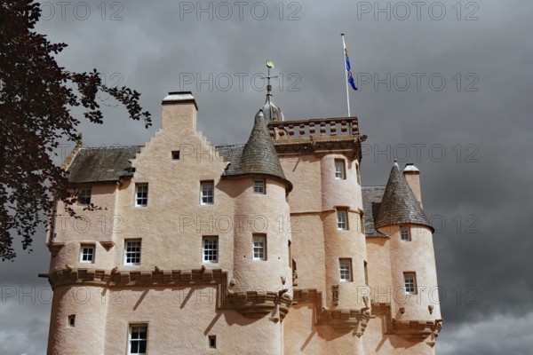 Pink castle with towers and banner in front of a threatening, cloudy sky, Craigievar Castle, Aberdeenshire, Scotland, Great Britain