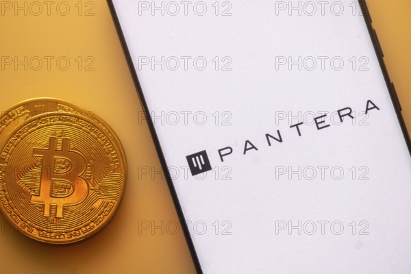 Bitcoin coin next to smartphone displaying Pantera logo on a white screen