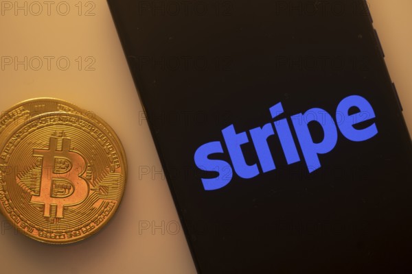 Bitcoin coin next to smartphone displaying the Stripe logo on a black background
