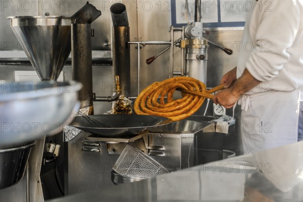 Man preparing tasty traditional churros in Seville, Spain