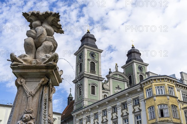 Baroque sculpture next to a building with towers and cloudy sky, Old Cathedral Ignatius Church Old Town Linz Upper Austria Austria