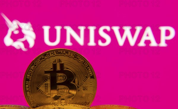 Dhaka, Bangladesh- 09 Sep 2025: Close-up of Bitcoin coins with the Uniswap logo visible on a screen in the background