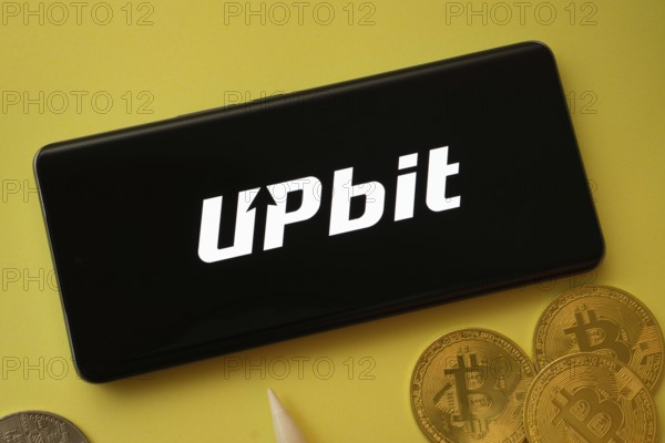 Dhaka, Bangladesh- 19 Sep 2025: Upbit logo on smartphone screen near Bitcoin coin and QR code on background