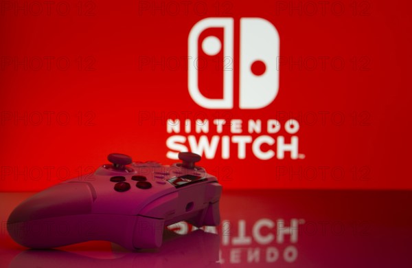 Dhaka, Bangladesh- 15 July 2025: Smartphone with nintendo switch logo, game controller, and earbuds on a yellow background