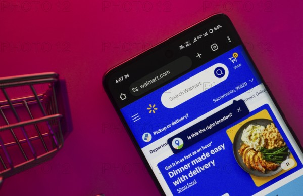 Dhaka, Bangladesh- 23 June 2025: A smartphone displaying the Walmart website with a shopping cart is shown on a vibrant background