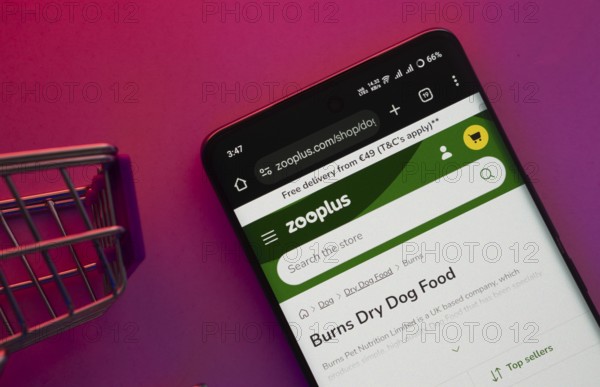 Dhaka, Bangladesh- 23 June 2025: A smartphone displaying the zooplus website with a shopping cart is shown on a vibrant background