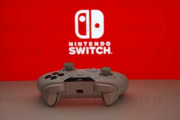 Dhaka, Bangladesh- 15 July 2025: Smartphone with nintendo switch logo, game controller, and earbuds on a yellow background
