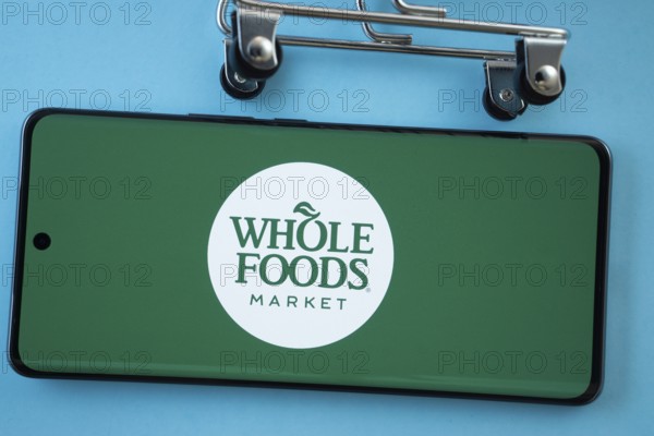 Dhaka, Bangladesh- 03 July 2025: Smartphone screen showing the Whole Foods Market logo with shopping cart wheels on a blue background