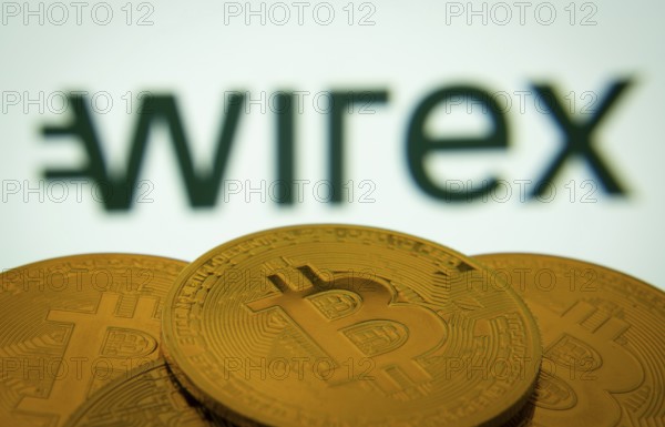 Dhaka, Bangladesh- 18 Sep 2025: Close-up of Bitcoin coins with thex wirex logo visible on a screen in the background
