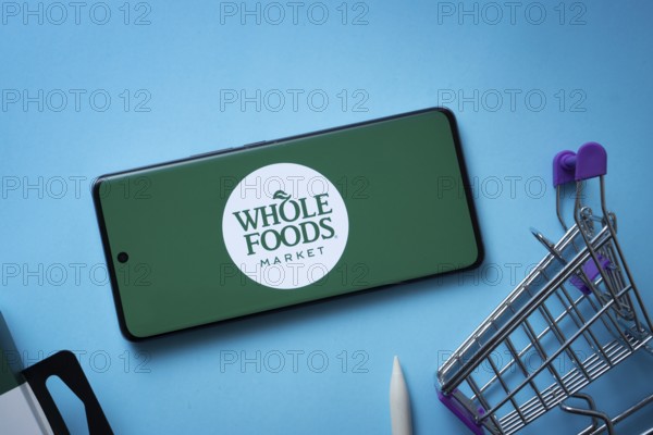 Dhaka, Bangladesh- 03 July 2025: Smartphone displaying Whole Foods Market logo with shopping cart on a blue background