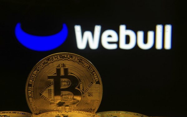 Dhaka, Bangladesh- 04 April 2025: Close-up of Bitcoin coins with the webull logo visible on a screen in the background