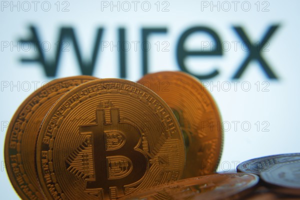 Dhaka, Bangladesh- 02 June 2025: Close-up of Bitcoin coins with the wirex logo visible on a screen in the background