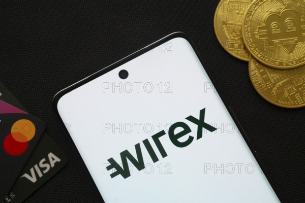 Dhaka, Bangladesh- 15 June 2025: Smartphone displaying wirex logo surrounded by Bitcoin coins and payment cards