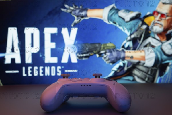 Dhaka, Bangladesh- 19 Sep 2025: A close-up of a white gamepad with the Apex Legends seen on screen in the background