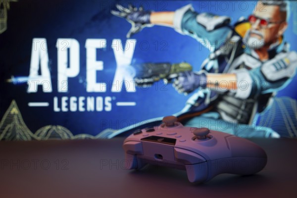 Dhaka, Bangladesh- 19 Sep 2025: A close-up of a white gamepad with the Apex Legends seen on screen in the background