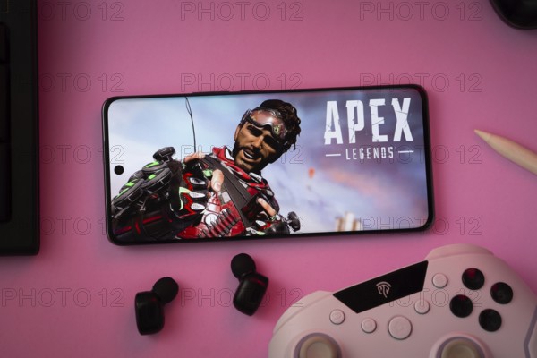 Dhaka, Bangladesh- 19 Sep 2025: A close-up of a white gamepad with the Apex Legends mobile seen on screen in the background