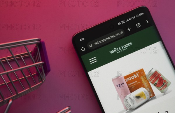 Dhaka, Bangladesh- 23 June 2025: A smartphone displaying the Whole Foods Market website with a shopping cart is shown on a vibrant background