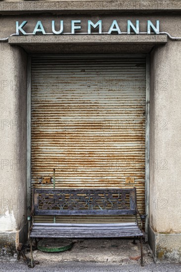 In front of a closed merchant's shop with a rusty Tor tor stands an old bench that suggests a bygone era, Weinviertel Lower Austria Austria