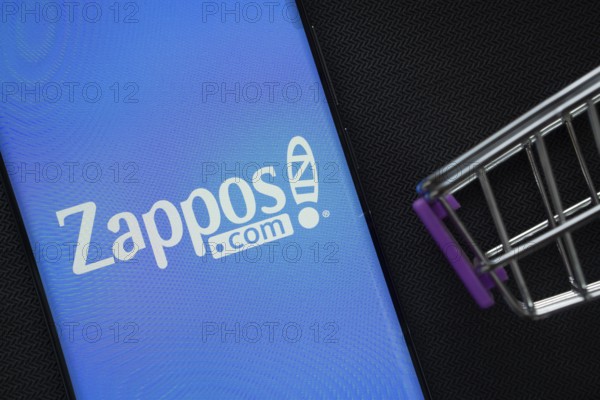 Dhaka, Bangladesh- 03 July 2025: A smartphone displaying the Zappos logo next to a miniature shopping cart on a background