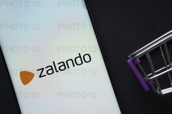 Dhaka, Bangladesh- 03 July 2025: A smartphone displaying the Zalando logo next to a miniature shopping cart on a background