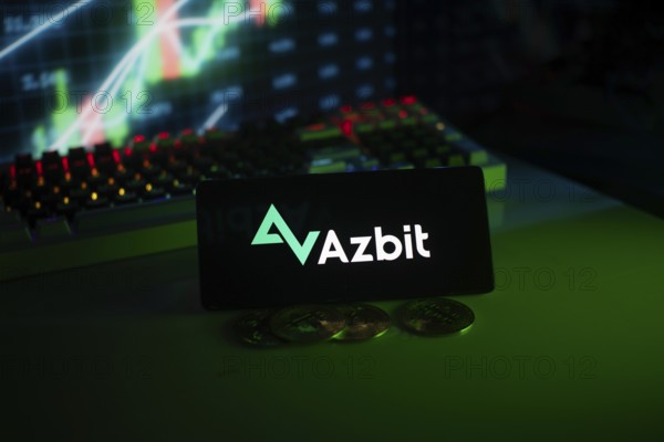 Azbit logo on phone, displayed with coins and stock chart, emphasizing finance and technology