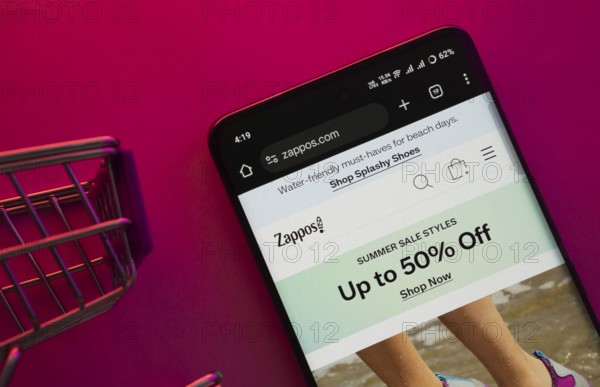 Dhaka, Bangladesh- 23 June 2025: A smartphone displaying the Zappos website with a shopping cart is shown on a vibrant background